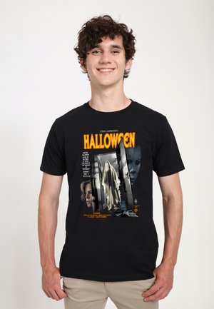 T-shirt in cotone nero con grafica del poster del film "Halloween" in arancione, bianco e grigio, raffigurante una figura spettrale e due personaggi.