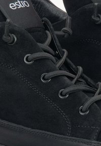 Czarne zamszowe sneakersy z czarnymi sznurówkami, metalowymi oczkami i teksturowaną gumową podeszwą. Na języku znajduje się logo 'estro'.