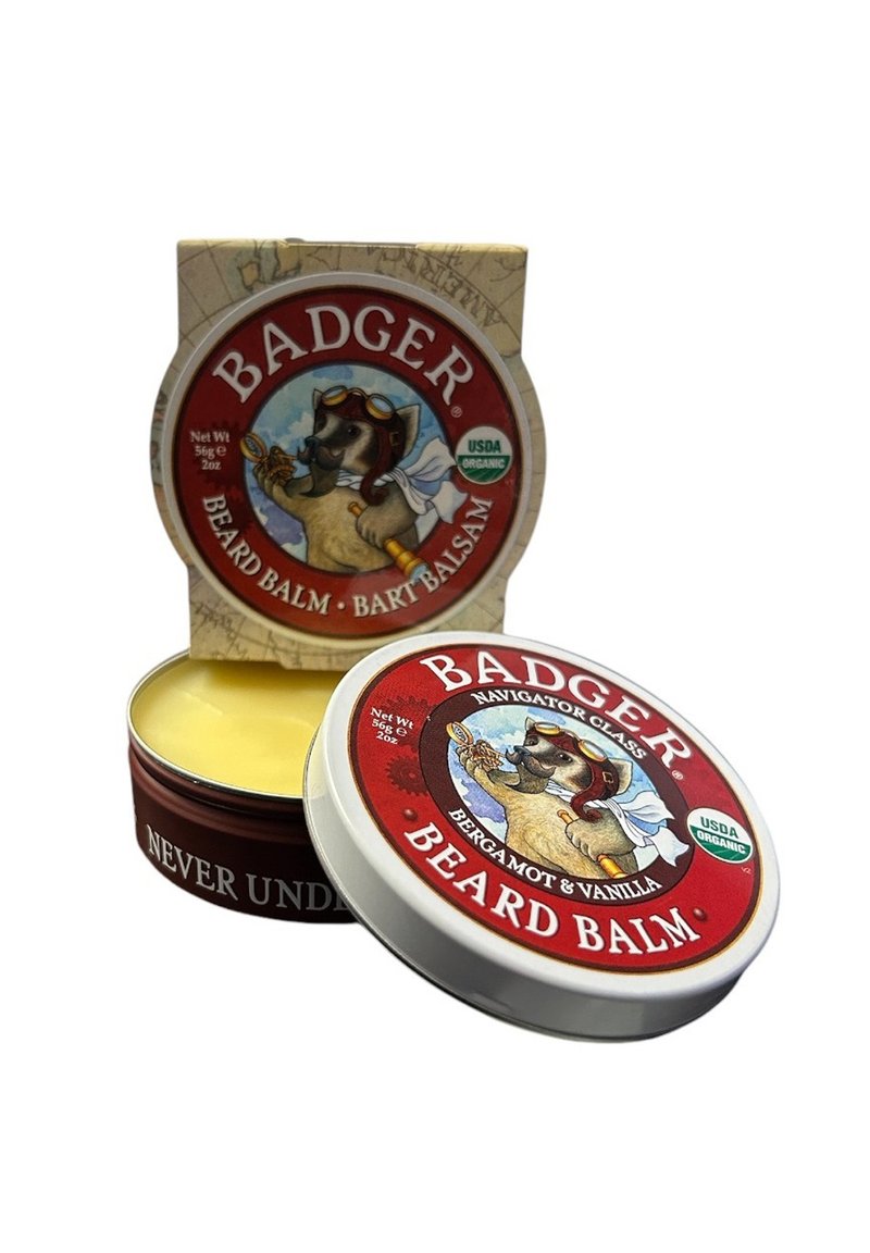 Dachsbeard-Balsam in einer runden Dose mit einem roten Etikett, das einen Hund mit Sonnenbrille zeigt. Im Inneren befindet sich ein glatter, gelber Balsam. Die Verpackung umfasst eine dekorative Box.