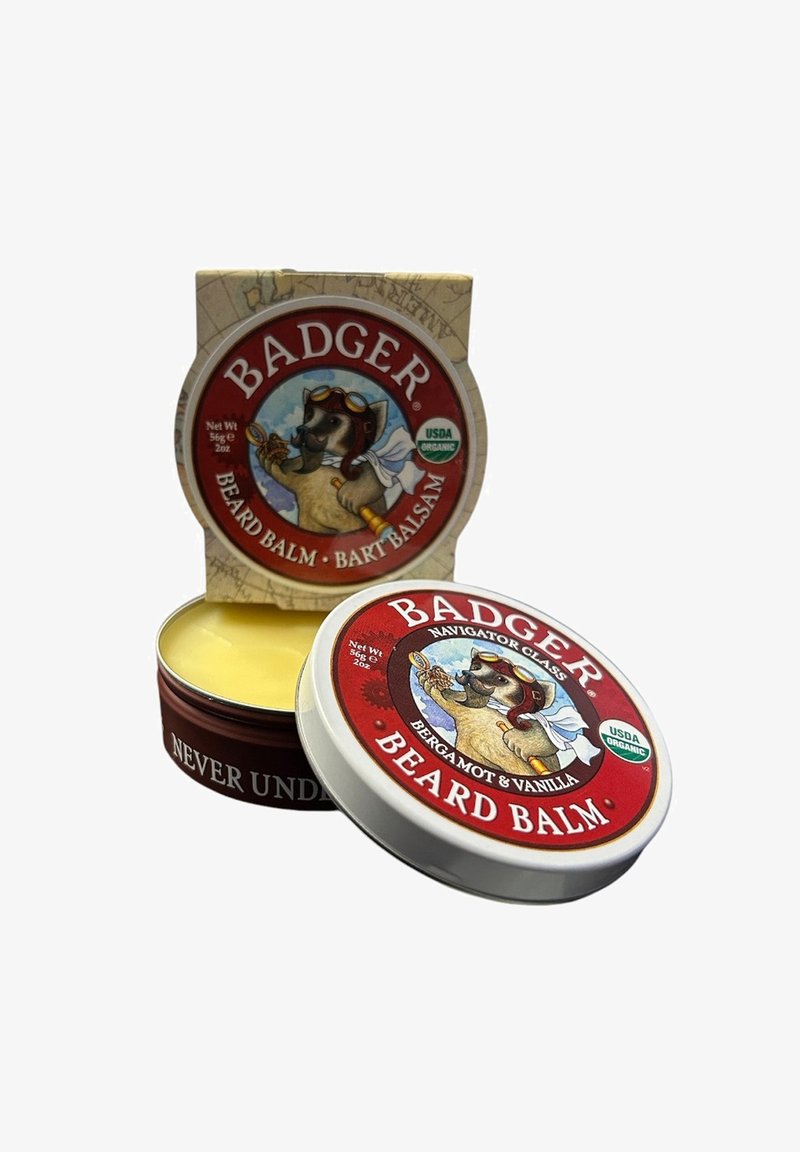 Dachsbeard-Balsam in einer runden Dose mit einem roten Etikett, das einen Hund mit Sonnenbrille zeigt. Im Inneren befindet sich ein glatter, gelber Balsam. Die Verpackung umfasst eine dekorative Box.