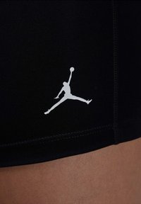 Fekete atlétikai rövidnadrág rugalmas anyagból, fehér Jumpman logóval. Varrott részletek és testhezálló kivitel a teljesítmény érdekében.