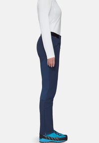 Marineblauwe outdoorbroek met een getailleerd ontwerp, gestructureerde kniestukken en oppak zakken; gecombineerd met blauwe en zwarte wandelschoenen.