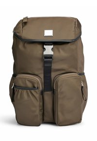 Ruskea reppu, jossa on kaksi etupuolen vetoketjullista taskua, ylhäällä kansi, joka on kiinni metallisoljella, sekä pieni brändilogo kannessa.