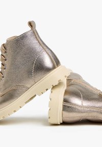 Metallisch goldene Knöchelstiefel mit strukturiertem Lederoberteil, hellem Gummisohle und Schnürdesign mit sechs Ösen. Mit robustem, rundem Zehenbereich.