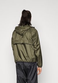 Grön lättviktsjacka med huood, med insydd midja och dragkedjefickor. Slät textur och avslappnad passform.