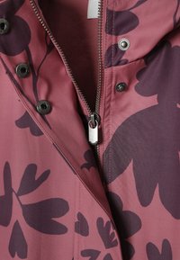 Makroülesvõte tume lillemustriga burgundia jope keskmise metallist tõmbluku ja ümberringi olevate klambritega.