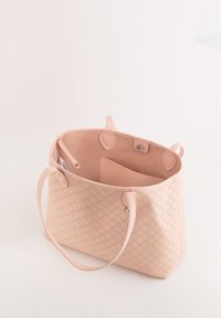 Sac fourre-tout rose avec un motif hexagonal texturé, design à ouvertue sur le dessus, et deux poignées. L'intérieur comporte une petite poche. Matériau en cuir lisse.