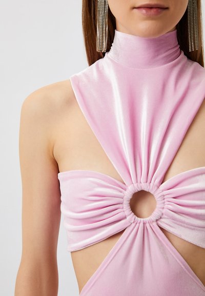 Rotes Samtkleid mit hohem Kragen, ausgeschnittenem Vorderteil und kreisförmigem Knotendetail sowie glatter Textur. Akzentuiert mit langen, metallischen Ohrringen.