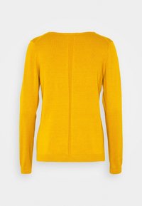 Pull over en tricot jaune à manches longues avec un col rond, présentant un détail de couture central et un ourlet et des poignets côtelés. Texture douce et forme ajustée.