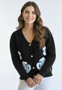 Czarny kardigan z haftem jasnoniebieskiej róży, dekolt w kształcie litery V, pięć ozdobnych guzików, ściągacze na mankietach i dole, miękka dzianinowa faktura.