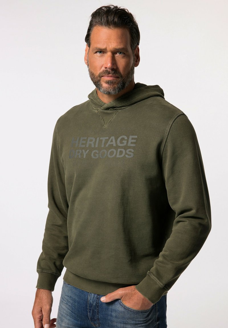Khaki groene hoodie van een zachte stof, met een grote grijze opdruk die "HERITAGE DRY GOODS" op de borst zegt en een koord in de capuchon.