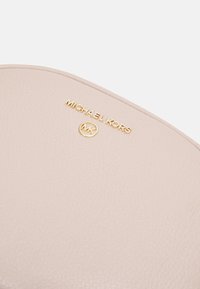 Monedero de cuero texturizado rosa con el logo en oro embossado "MICHAEL KORS" y emblema circular MK. Acabado liso, diseño minimalista.