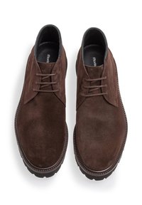 Scarpe in suede marrone con punta rotonda, design classico con lacci e suola in gomma; presentano cuciture tonali e una texture liscia.