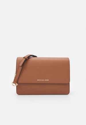 Hnědá kožená kabelka přes rameno s nastavitelným páskem a zlatým logem "MICHAEL KORS" na přední klopě na bílém pozadí.