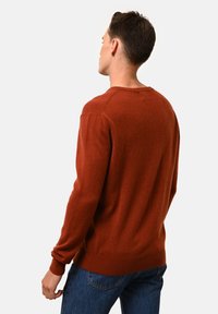 Maglione color ruggine realizzato in morbido tessuto, con maniche lunghe, polsini a coste e scollatura rotonda, dal taglio rilassato.