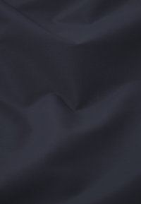 Dunkel marineblauer Stoff mit subtilen Falten und einer glatten, gewebten Textur unter sanfter Beleuchtung.