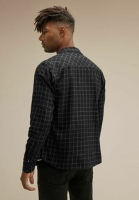 Svart rutig skjorta med grå rutmönster, långa ärmar och knappade manschetter. Mjuk tygkvalitet med krage och skräddarsydd passform.