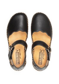 Zapatos de cuero negro con bordes festoneados y una correa ajustable. Plantilla de cuero natural, detalle trenzado a lo largo de la suela.