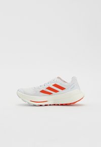 White athletic shoe with grey mesh upper, prominent orange stripes, padded collar, cushioned sole, and textured red outsole.