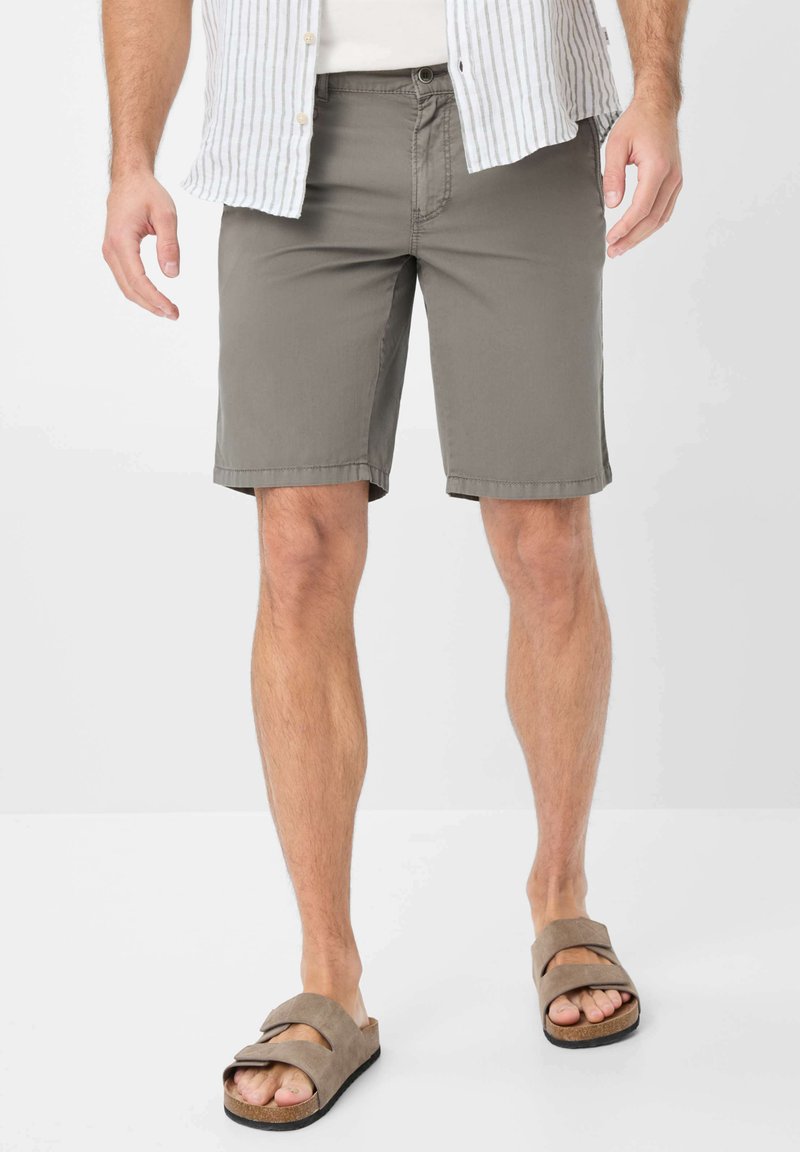 Pantaloni corti da uomo grigi realizzati in un tessuto morbido, con un taglio dritto, cuciture in vista e tasche laterali, abbinati a sandali scivolati marroni.