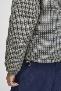 Quiltet puffer-jakke i beige og marineblå hundetannmønster, med snorhemp og teksturert stoff.