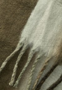 Sciarpa di lana in tonalità terrose di marrone e verde, con una superficie testurizzata e bordi sfilacciati per un tocco di dettaglio e contrasto.