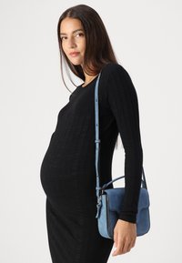 Μαύρο ριγωτό φόρεμα με μακριά μανίκια, εφαρμόστης κοπή. Ανοιχτό μπλέ σουέτ τσάντα χιαστί με λουρί. Λείος υφή και ορθογώνιο σχήμα.