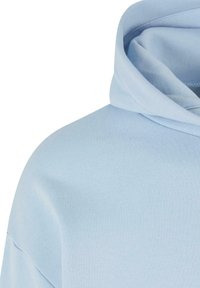 Tissu de sweat à capuche bleu clair, montrant l'épaule et une partie de la capuche avec des détails de couture visibles.
