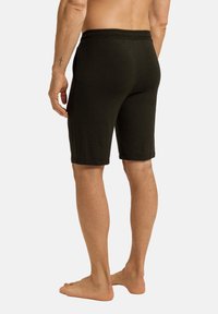 Zwarte katoenen short met een elastische tailleband, knielang ontwerp en zijzakken. De stof lijkt zacht en textuur te hebben.