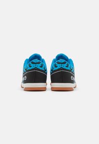 Zapatillas negras y azules con tejido texturizado, diseño sin cordones, un patrón azul prominente en la parte trasera y suelas de goma para mayor tracción.