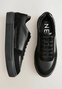 Schwarze Sneakers aus Wildleder und synthetischem Leder, mit einer strukturierten Sohle, Schnürdesign und kontrastierenden Materialien.