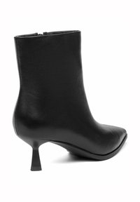 Zwarte leren enkellaars met een spitse neus en een korte, taps toelopende hak. Gladde textuur met een rits aan de achterkant.