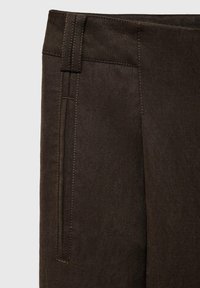 Bruine op maat gemaakte broeken met een gladde textuur, voorzien van zijzakken en zichtbare stiksels langs de naden.