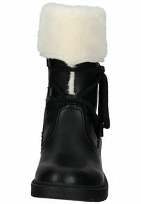 Botte en cuir noir avec un revers en fausse fourrure blanche, bout rond, fermeture à lacets noire et détails de surface texturée. Semelle en caoutchouc durable.