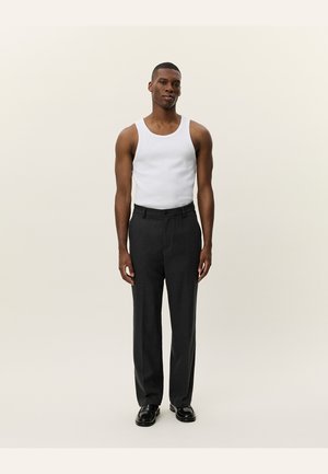 Black dress pants with a tailored fit, paired with a white tank top. The fabric is smooth, and pants have a subtle sheen. Black shoes complete the look.