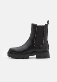 Stivale Chelsea nero alla caviglia in pelle liscia con pannelli laterali elasticizzati, suola spessa e linguetta sul retro per un facile indosso.