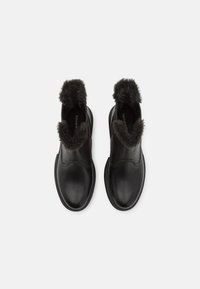 Botas de tobillo de cuero negro con un forro de piel de fur gris texturizado en el puño, que presentan un acabado suave y un diseño de punta redondeada.