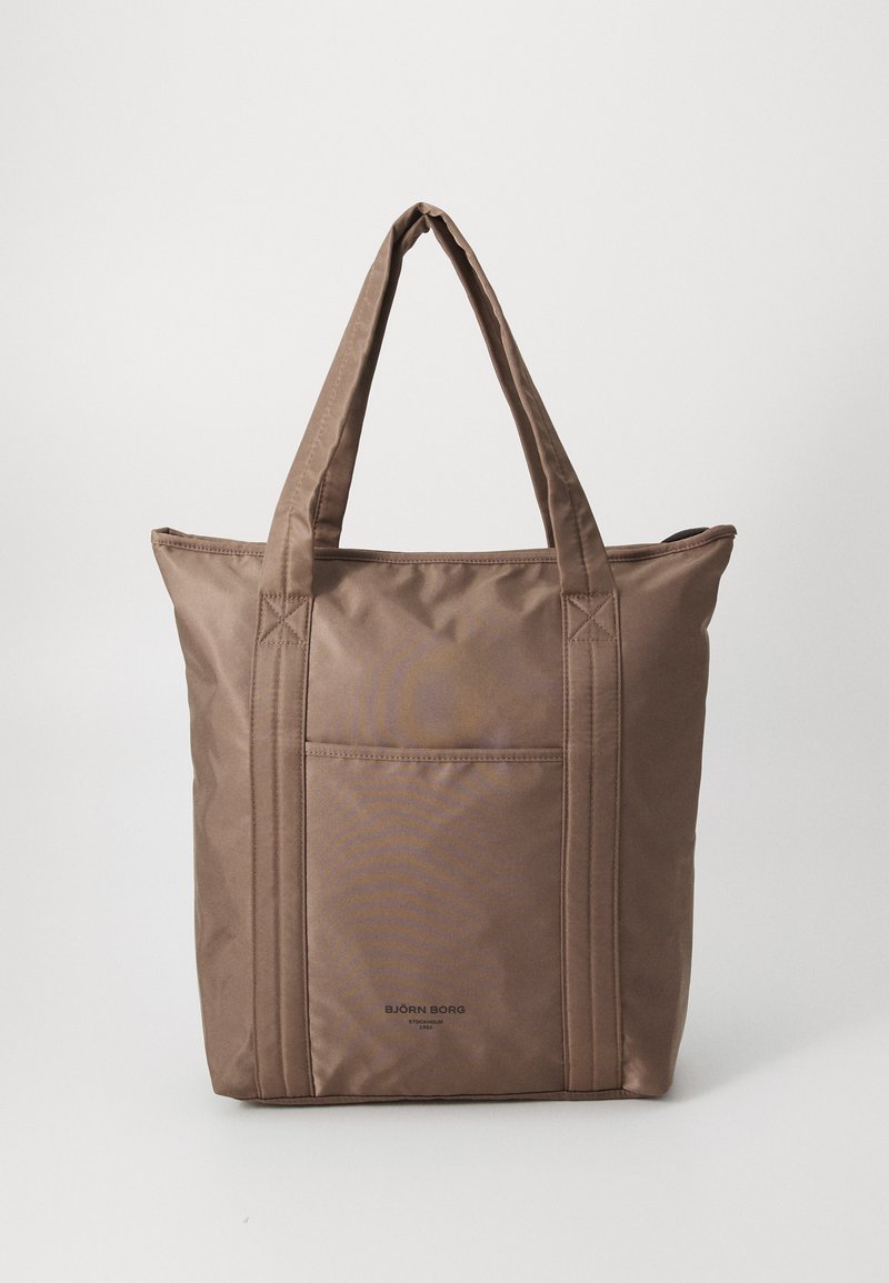 Brown nylon tote bag with dual handles, featuring a front pocket and stitched detailing. Smooth texture, rectangular shape, and minimal branding.