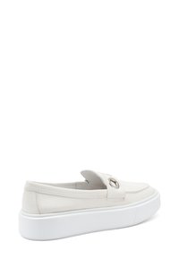 Scarpa bianca in pelle senza lacci con punta arrotondata, fibbia decorativa e suola spessa bianca. Texture liscia e design minimalista.