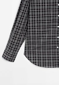 Chemise à carreaux noir et blanc à manches longues avec des boutons blancs, montrant le devant et une manche sur fond blanc.