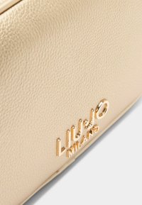 Gouden tas met een gestructureerd leren oppervlak. Bevat het reliëflogo "LIU JO MILANO" in glanzend metaal. Rechthoekige vorm.