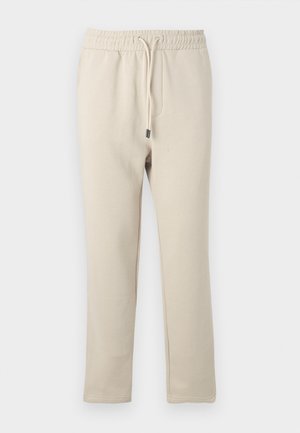 Pantalons de survêtement beiges avec une taille élastique et un cordon de serrage. Fabriqués en tissu doux, avec des jambes fuselées et des poches latérales.