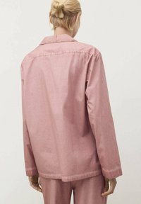 Giacca di cotone rosa con colletto a scollo, maniche lunghe e vestibilità rilassata. Texture liscia con dettagli di cucitura lungo le cuciture.