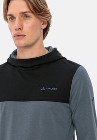 Felpa con cappuccio in nero e grigio, caratterizzata da una morbida texture, logo sul petto e blocchi di colore a contrasto.