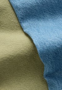 Twee stofstaaltjes, één in gestructureerd blauw denim en de ander in olijfgroen, overlappen elkaar en tonen hun geweven patronen en kleuren.
