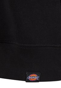 Mustat puuvillaneuleet, jossa on ribbikuvio, ja pienen värikkään Dickies-logotunnuksen ommel helmaan. Yksinkertainen muotoilu ja kestävä ompelu.