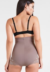 Shapewear a vita alta in marrone chiaro con bordo in pizzo. Caratterizzato da una consistenza liscia e elastica e spalline nere regolabili sul retro.