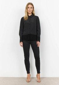 Black shirt with a smooth finish, featuring a lace hem and cuffs, buttoned front, classic collar, paired with black fitted pants.