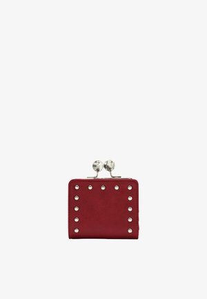 Czerwona kwadratowa portmonetka z srebrnymi metalowymi ćwiekami wzdłuż krawędzi i zapięciem z dwoma okrągłymi gałkami przypominającymi marmur.
