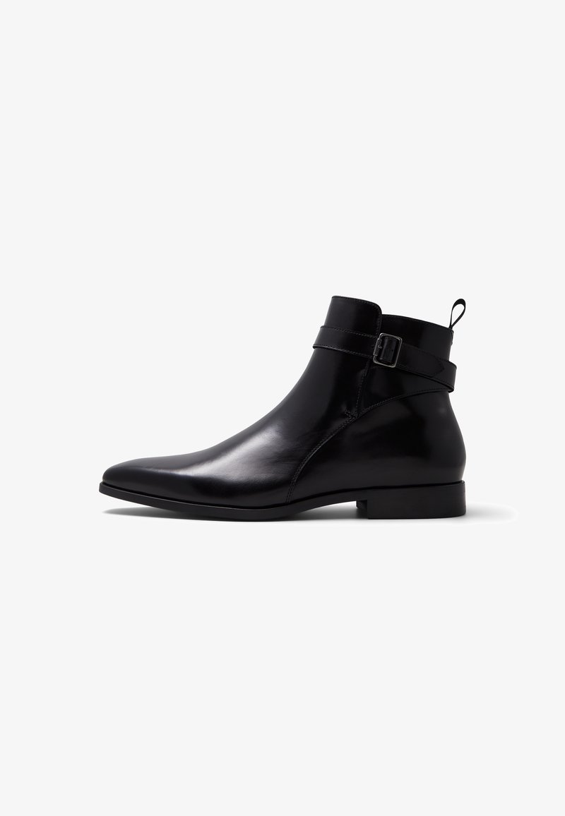 Bottine en cuir noir poli avec bout pointu, bride à boucle latérale, talon bas et languette à l'arrière, vue de profil sur fond blanc.